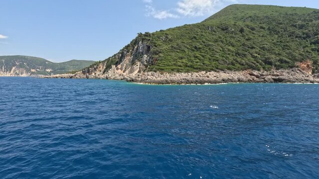 Scenic boat journey along the rocky coastline of Ithaca Island in the Ionian Sea, Greece. Deep blue Mediterranean waters, green hills and dramatic coastal cliffs create a stunning summer travel