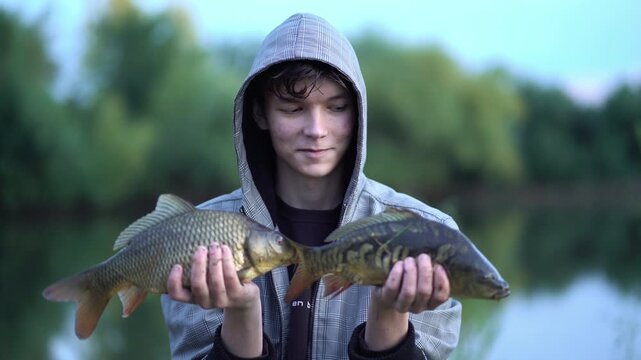 fisherman holding two carp, showing his catch to the camera