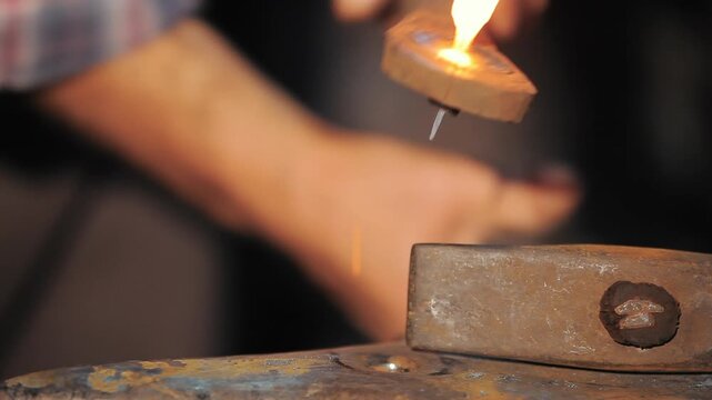 Macro shot of traditional metalworking as a craftsman hits a red hot iron piece, creating sparks.