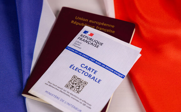 Une carte &eacute;lectorale et un passeport pour aller voter. En arri&egrave;re plan, le drapeau de la France. 30 juin 2026 - Paris, France