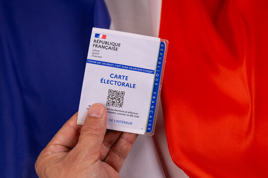 Une personne pr&eacute;sentant sa carte &eacute;lectorale pour aller voter. En arri&egrave;re plan, le drapeau de la France. 30 juin 2026 - Paris, France