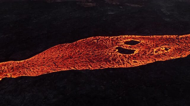 Flowing lava stream across dark volcanic rock