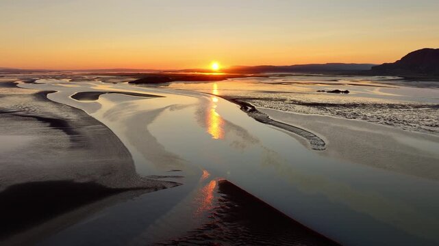Aerial estuary sunset showing braided tidal channels and receding tide