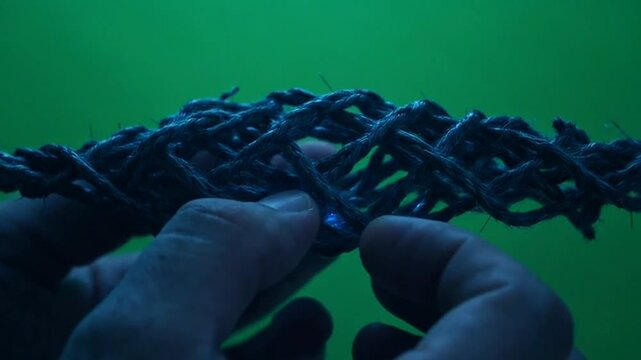 Hands inspecting carbon fiber lattice structure on green screen.