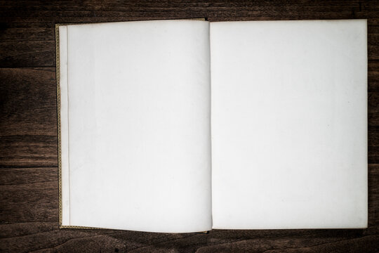 Libro antiguo abierto con p&aacute;ginas en blanco sobre mesa de madera r&uacute;stica1