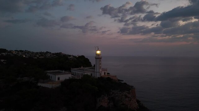 Cabo de la Nao lighthouse at twilight with illuminated beacon overlooking Mediterranean coast and Javea on Costa Blanca