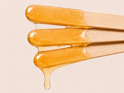 Golden Sugaring Wax Stretching Between Wooden Spatulas