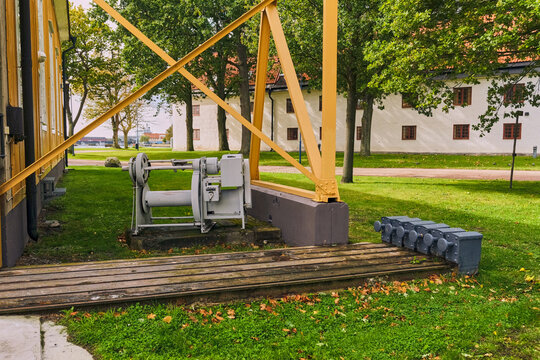 Karlskrona, Sweden - 16 September 2025: View of historic naval machinery and a yellow structure on Stumholmen island, UNESCO World Heritage site Karlskrona naval port.
