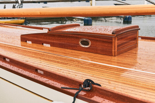 Karlskrona, Sweden - 16 September 2025: View of the polished wooden deck and cabin top of a vintage racing yacht covered in raindrops in the harbour.