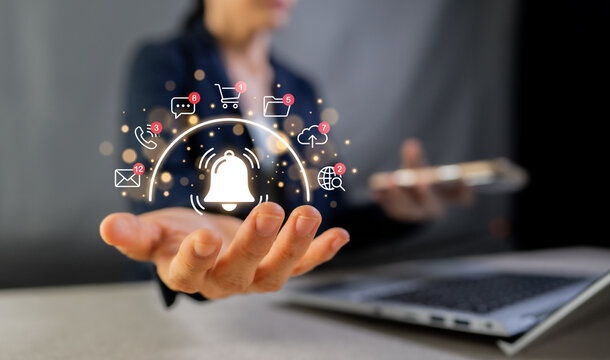 Businesswoman holding notification bell icon with digital marketing, email and social media alerts