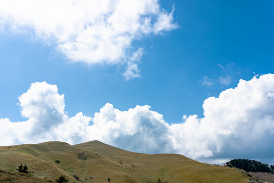 olling Grass Hills Under Blue Sky and Dramatic White Clouds