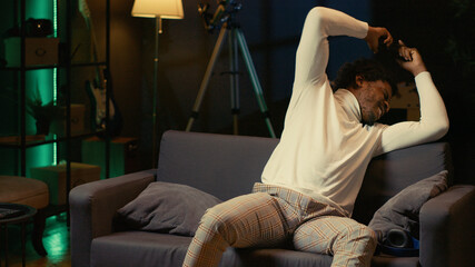 African American player shouting after failing to win video game, doing frustration gestures, upset gamer on couch in apartment ready to throw gamepad controller, raging after game over. © DC Studio