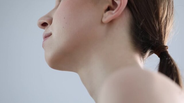 Artist removing makeup from woman's face indoors, closeup
