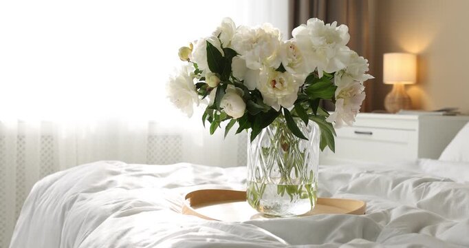 Bouquet of beautiful peony flowers on bed at home. Camera moving left