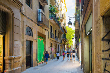 Fototapeta premium A narrow pedestrian street of with garden balconies and shops in the Gothic Quarter of Barcelona, Spain.