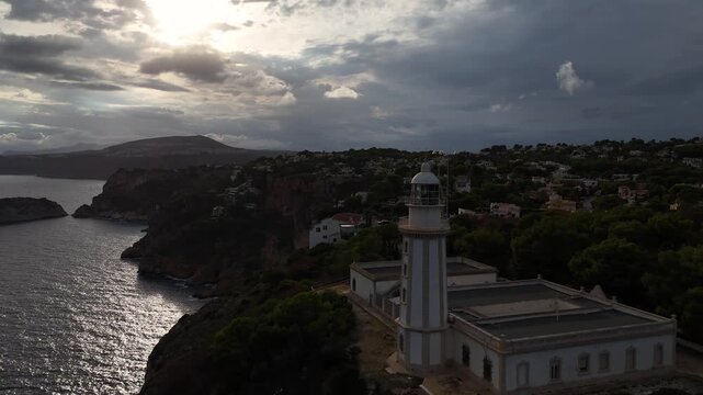 Faro de Cabo de la Nao lighthouse on rocky Mediterranean cliffs with turquoise seascape and dramatic cloud formations