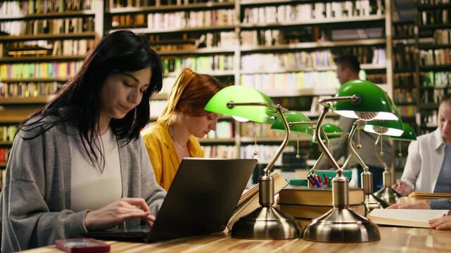 Student ignoring laptop work and notes after phone notification, illustrating digital distraction, procrastination and lost concentration in quiet library.