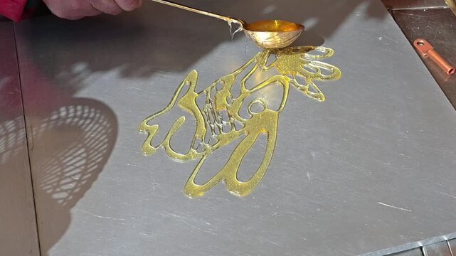Close-up of elderly Chinese master's hands making traditional sugar painting of a rabbit holding carrot on marble slab