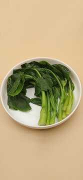High angle view of blanched Chinese broccoli arranged on a white ceramic plate.