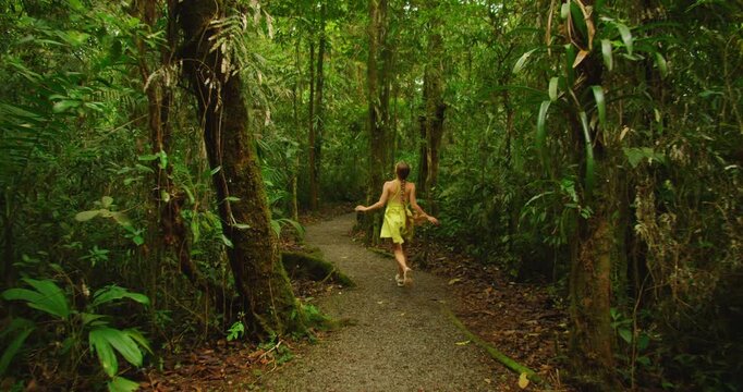 Traveler joyfully running along tropical forest path toward Blue Falls during Costa Rica adventure