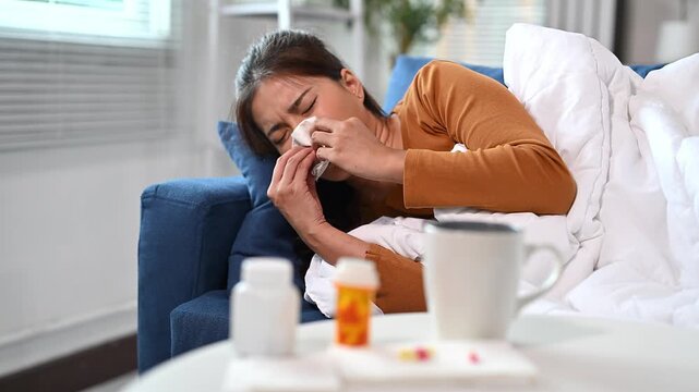 Woman in bed frustrated with pill bottles and medicine on bedside table
