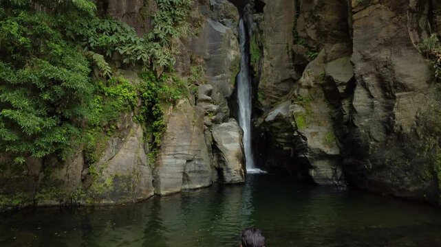 Young fit man standing in front of a waterfall pool in azores. Salto do Cabrito, Sao Miguel.