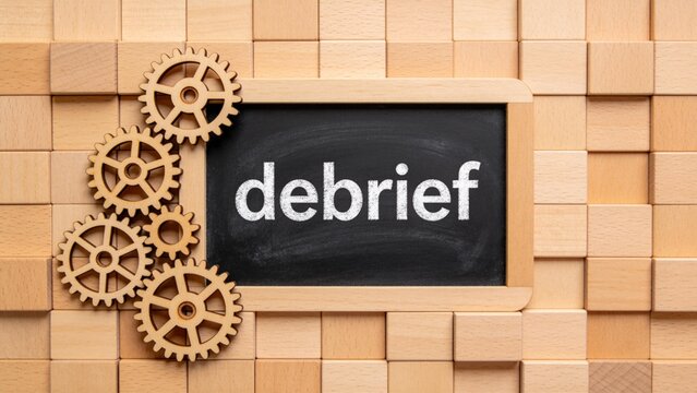 Wooden gears and chalkboard with word debrief