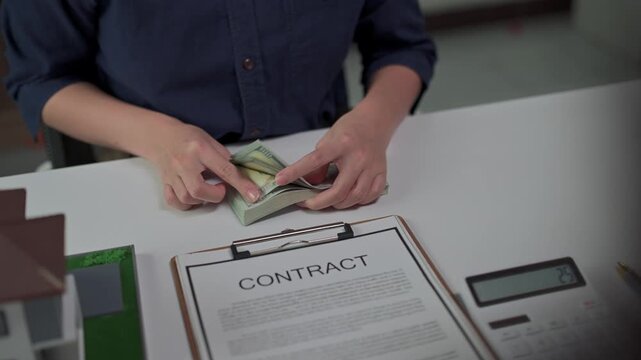 Real estate agent counting money for house contract