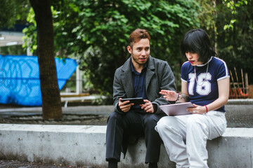 Obraz premium Young Hispanic man and woman playing a mobile video game outdoors in Mexico City