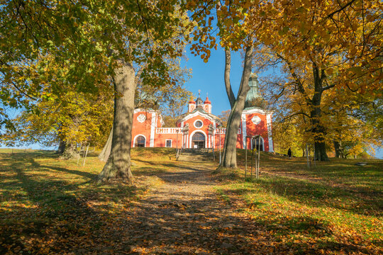 View of the Kalvaria Banska Stiavnica baroque church complex framed by autumn trees with yellow foliage under a clear blue sky in Banska Stiavnica, Banskobystricky kraj, Slovakia.