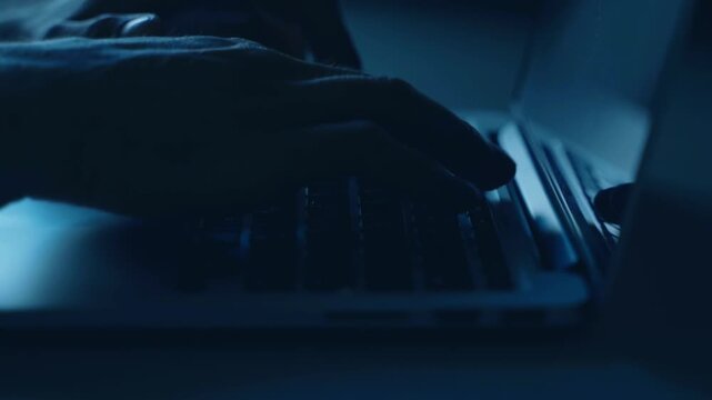 Freelancer Male Hands Typing on Laptop Keyboard in Low Light with Screen Reflection in 4K Ultra HD footage
