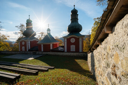 View of the Kalvaria Banska Stiavnica chapels with red walls and green domes under a bright sun starburst Banska Stiavnica, Banskobystricky kraj, Slovakia.