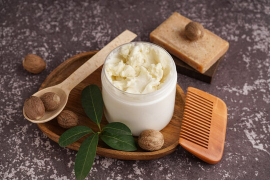 Composition with jar of shea butter, nuts, hair comb and soap on grunge color background