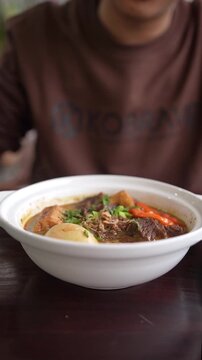 woman holding a bowl of beef stew with vegetables