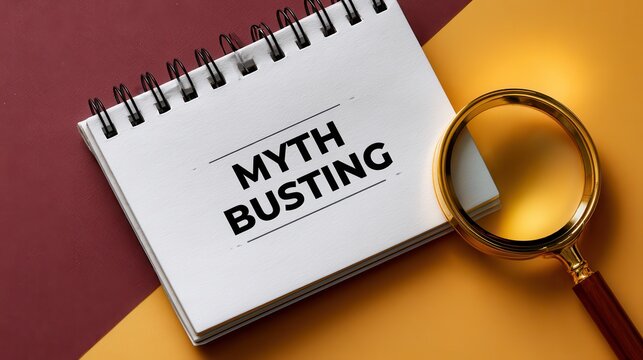 A spiral bound notepad with Myth Busting written on it next to a magnifying glass