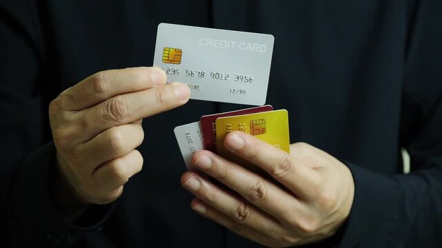 Close up of hand human holding multiple color credit cards, choosing a red card for payment, concept of consumerism, financial management, debt and cashless society and saving money	