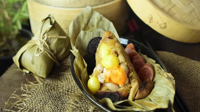 Warm Zongzi or Chinese traditional sticky rice dumpling with gentle steam rising, filled with salted egg yolk and mushroom, perfect for Dragon Boat Festival.