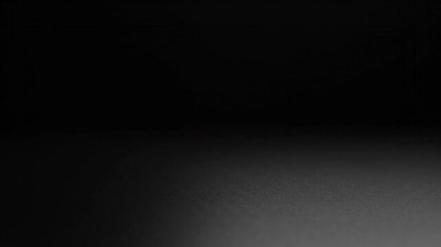 Dark empty studio background with soft floor light.