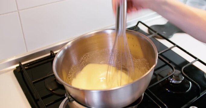 Cooking thermometer. Food preparation. Chef hand whisking yellow liquid in heating bowl. Controlling meal recipe professional process.