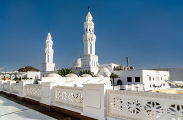 Obraz premium The white facade and minarets of Masjid al-Qiblatayn under a clear blue sky in Medina, Saudi Arabia