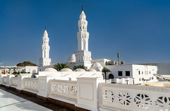 The white facade and minarets of Masjid al-Qiblatayn under a clear blue sky in Medina, Saudi Arabia
