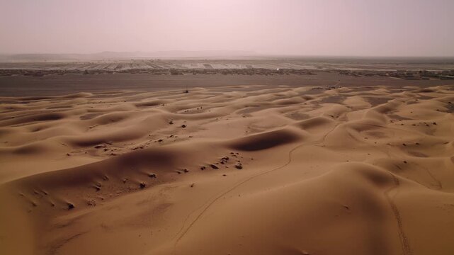 Erg Chebbi dune field extends across Merzouga, Errachidia Province, Dr&acirc;a-Tafilalet, Morocco, revealing aeolian landforms and caravan tracks, slow forward flyover shot.