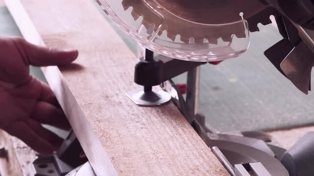 Joinery production. Circular saw work. Male hand clamping cutting wood plank in workshop with power rotary construction tool vice.