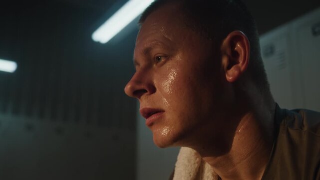 Close Up of Young Athlete Face Covered in Glistening Sweat Drops. Man Breathing Heavily with Open Mouth, Eyes Filled with Focus and Exhaustion, Resting in Locker Room After Grueling Training Session.