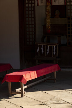 View of traditional red-covered benches and sacred shimenawa rope inside a peaceful temple courtyard in Nara, Nara, Japan.