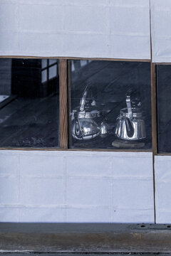 View of two reflective silver kettles sitting behind a glass window of a traditional building with white paper panels in Nara, Nara, Japan.