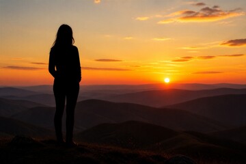 Obraz premium Woman standing watching sunset over rolling mountain ridges