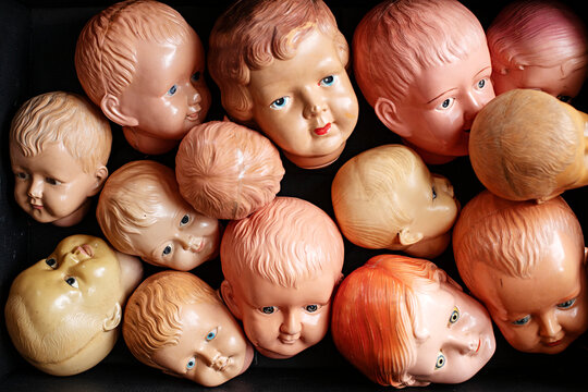 Collection of vintage doll heads scattered against a dark background