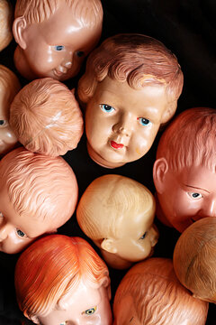 Collection of vintage doll heads scattered against a dark background