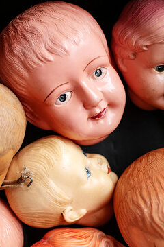 Collection of vintage doll heads scattered against a dark background